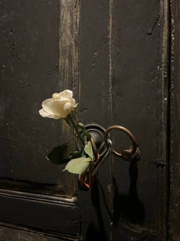 Floral offerings left at door and stone carving in Sukawati