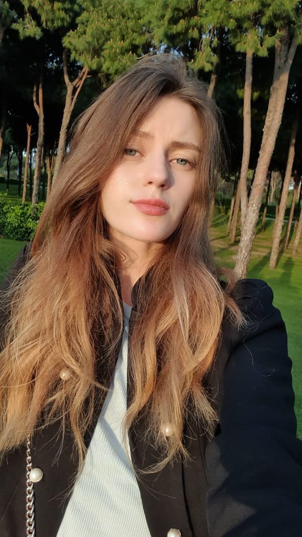 Woman in black blazer photographed among pine trees in Serik