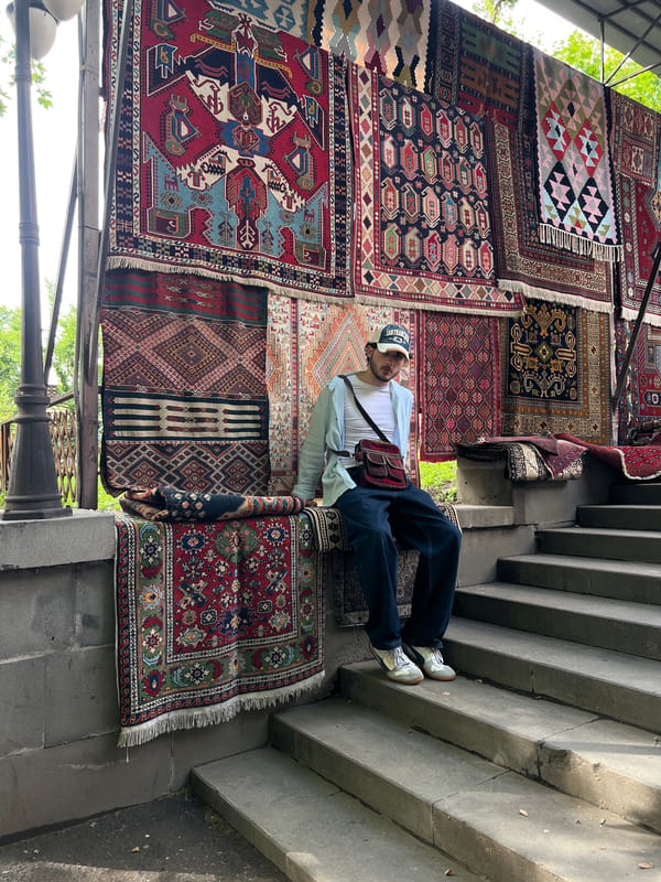 Man rests on rugs at Yerevan street market