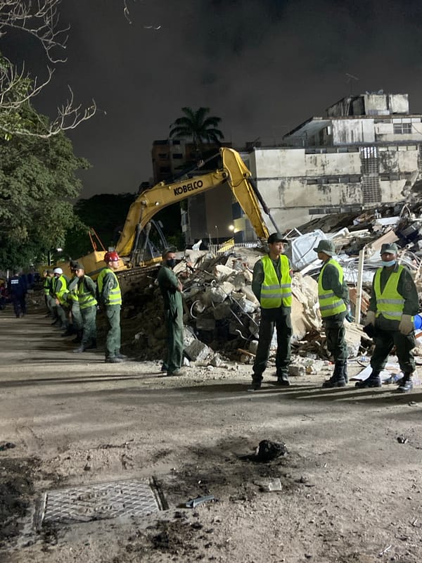 Nighttime building collapse response in Caracas, excavator on site