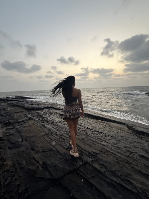 Woman stands on rocky coastline in Calangute, India