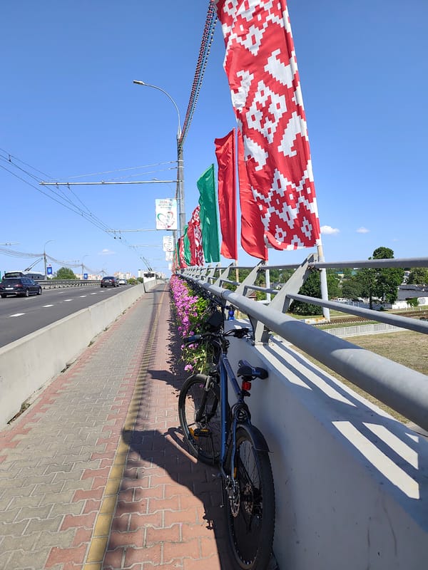 Brest bridge walkway: flowers, flags, and a parked bicycle