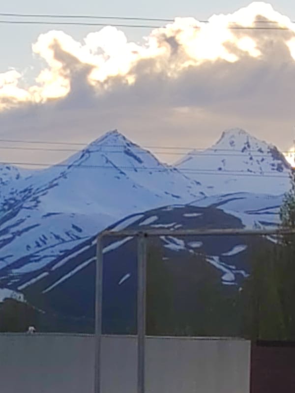 Snow-covered mountain peaks observed under cloudy skies
