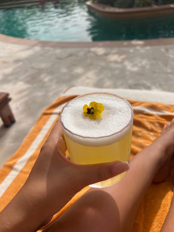 Person enjoys yellow cocktail with flower garnish in Dubai