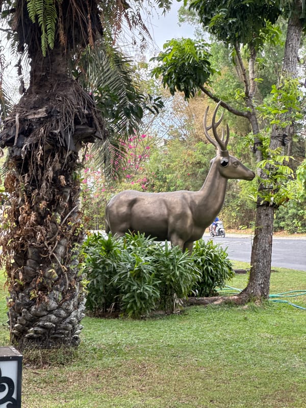 Balinese roadside grounds with sculptures, gates, and street life