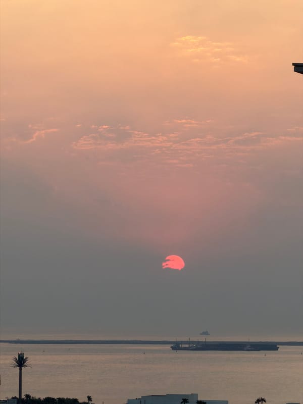 Sunset over Lusail's waterfront, sky glowing orange and pink