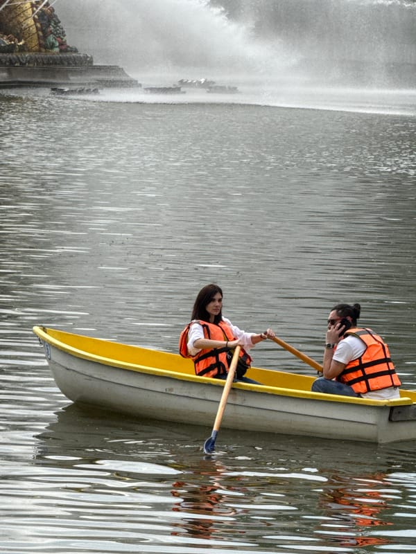 Women row boat near ornate fountain in Moscow park