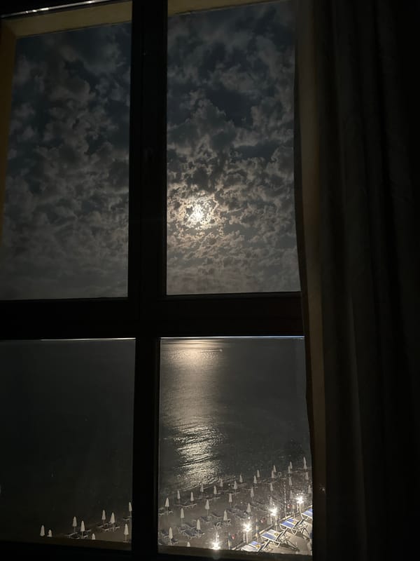 Moonlit beach view through a window in Nesebar at night