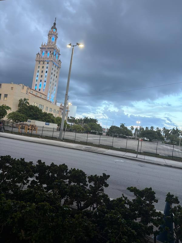 Freedom Tower lit up blue under cloudy Miami skies