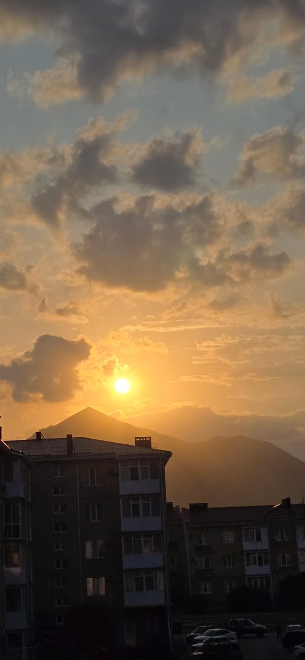 Sunset hour in Inozemtsevo — apartments, mountains, and an orange