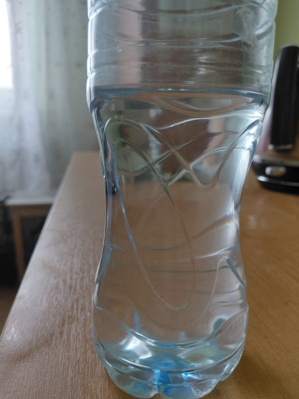 Craft materials and water bottle spotted on wooden surface
