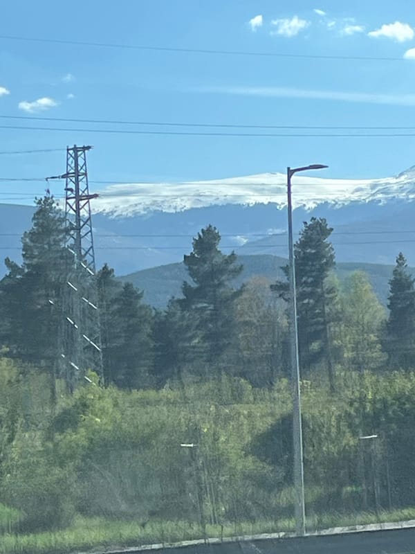 Vehicle travel through rural area with power lines, mountains