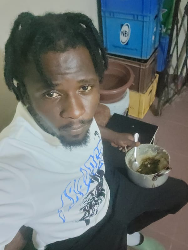 Man eats green vegetables from metal pot in Jos