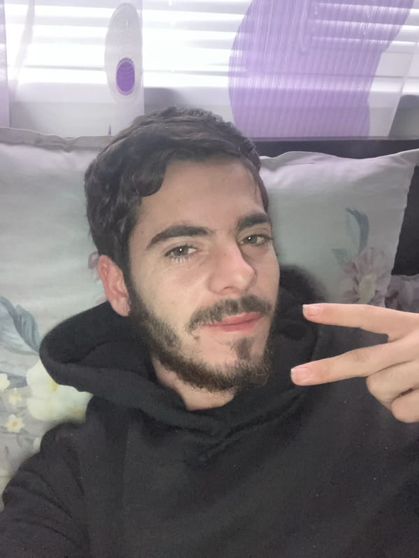 Person makes peace sign while resting on floral pillow
