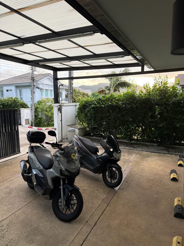 Two scooters parked under residential carport in Chalong, Thailand