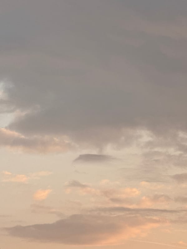 Person relaxes indoors with phone during cloudy Milan evening
