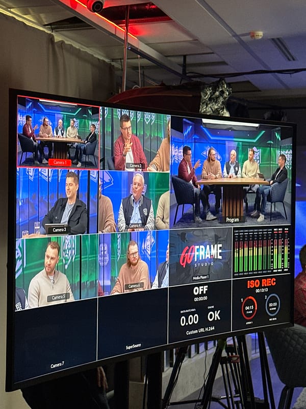 Five men filmed at table during broadcast production session