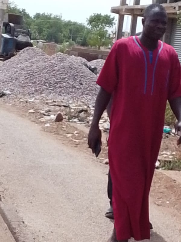 Man walks cracked road carrying object in Tamale Ghana