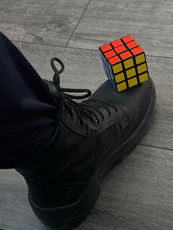 Person in uniform clothing observed with Rubik's Cube boot display