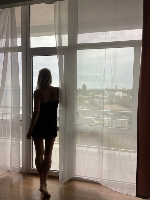 Woman opens curtains at dawn in Giachrypsh apartment