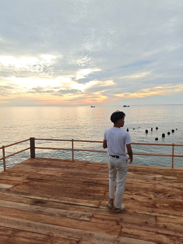 Person watches twilight from pier in Lhokseumawe, Indonesia