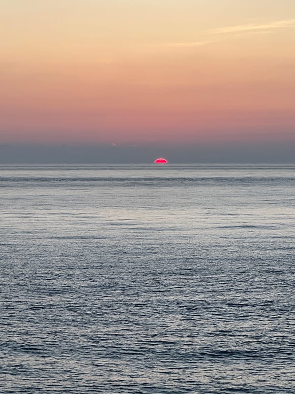 Red sun sinks into the South China Sea at dusk