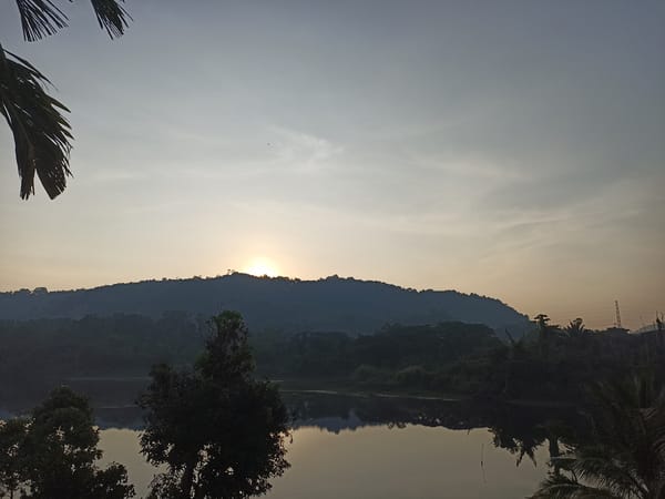 Sunrise or sunset captured over forested mountains in Kathu