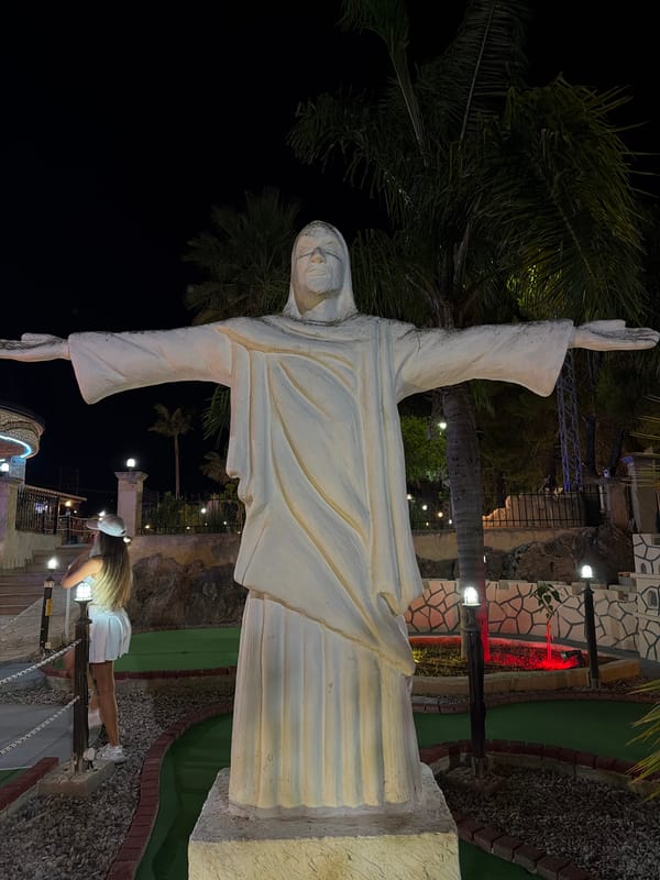 Nighttime mini-golf with a towering Jesus statue as centerpiece
