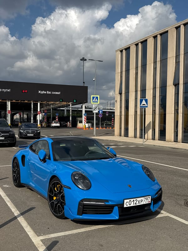 Bright blue Porsche 911 Turbo S parked outside modern Moscow building