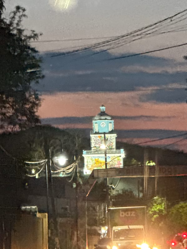 Evening traffic flows past decorated tower in Xochitepec