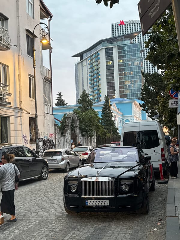 Cat on a Vespa, Rolls-Royce nearby — Batumi street scene