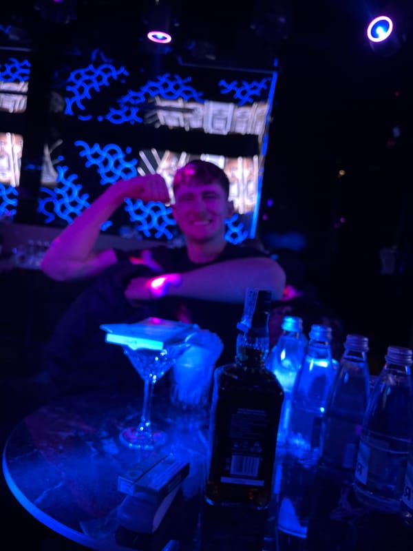 Person celebrates with raised fist in illuminated nightclub venue