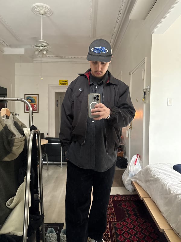 Person takes selfie wearing logo baseball cap in NYC apartment