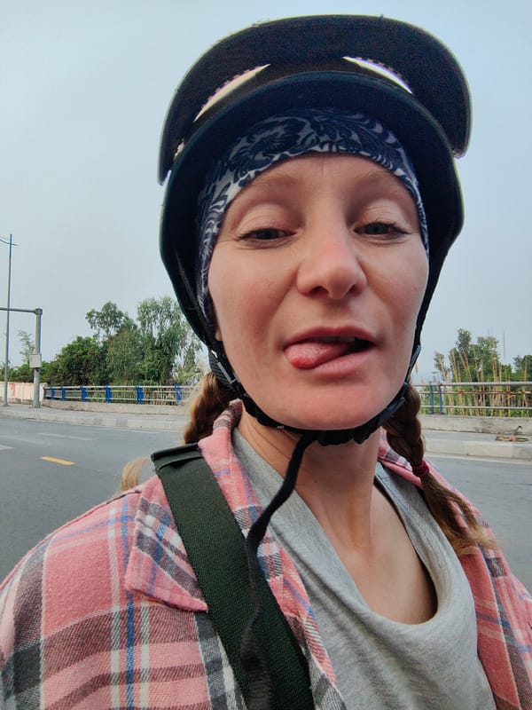Red-haired person in helmet sticks tongue out in Vietnam