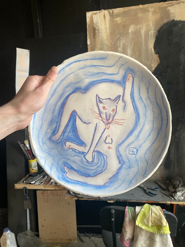 Artist displays handmade ceramic cat plate in Moscow studio