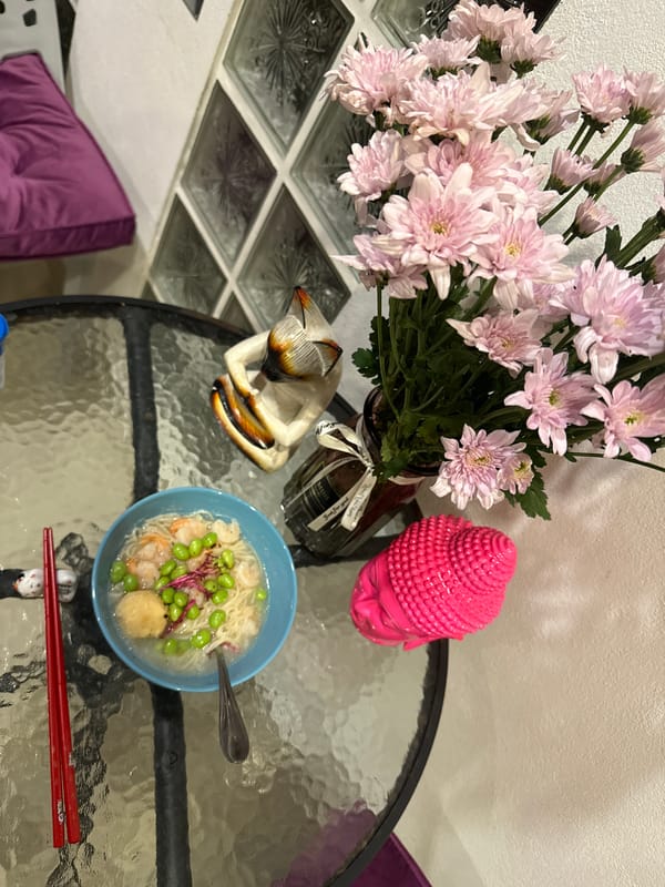 Pink flowers and Buddha statue arranged on Ko Samui table