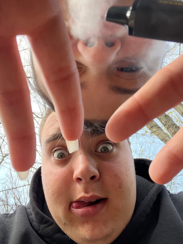 Two people spotted outdoors, one vaping among trees