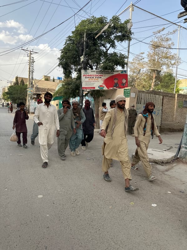 Seven men in traditional dress line street in Quetta