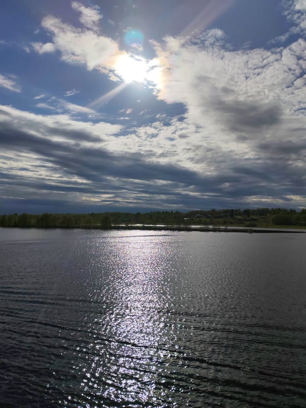 Sun rays pierce clouds over water in Zelonaya Roshcha