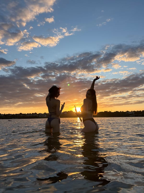 Wading in shallow water at golden hour, phones out.
