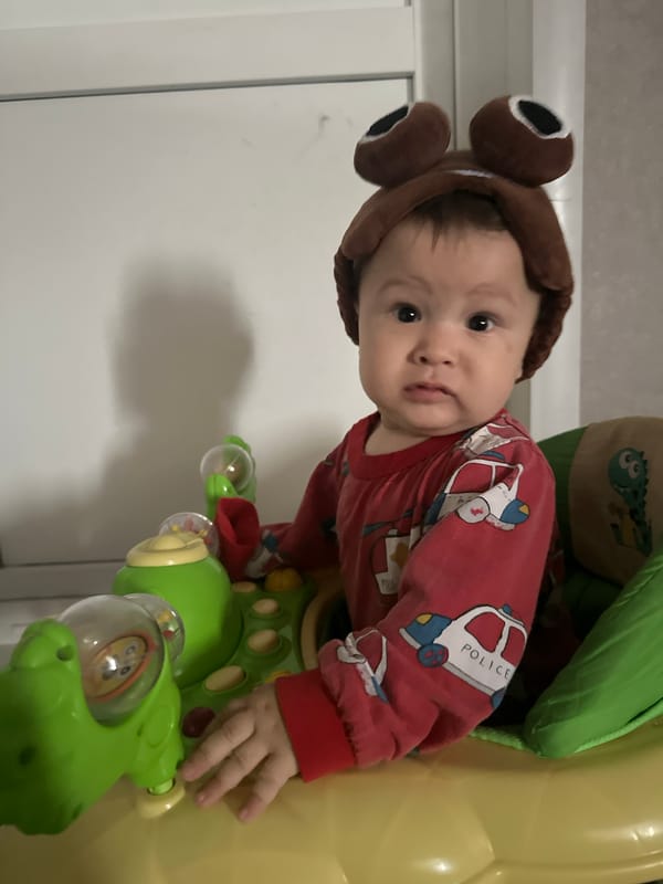 Baby in frog hat has big feelings in a colorful walker