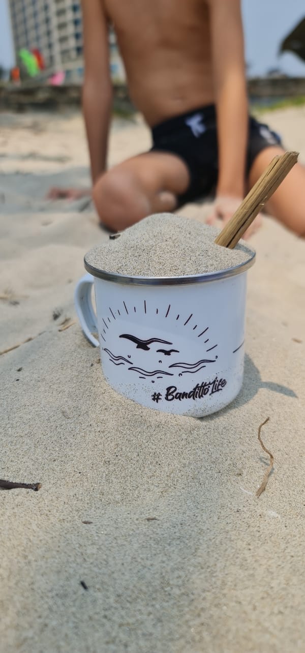 Child plays with sand-filled mug on Đà Nẵng beach