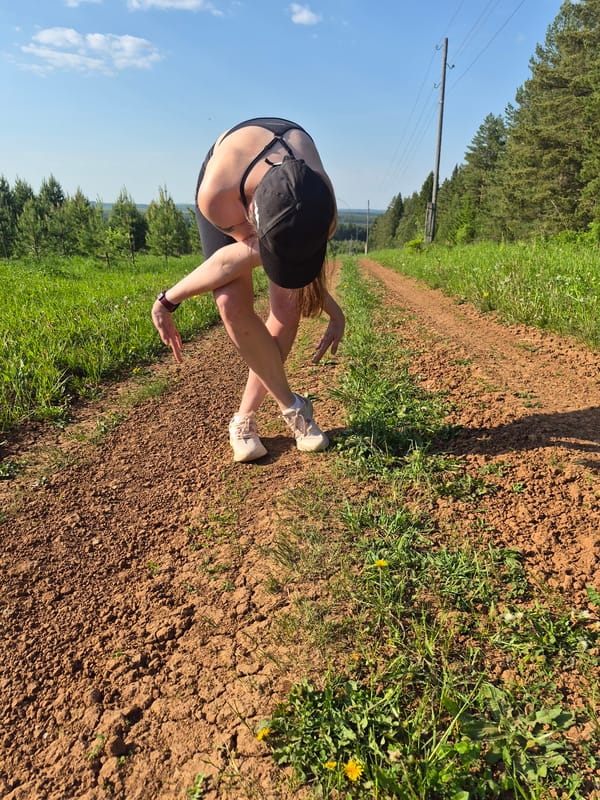Woman exercising on rural dirt road amid green landscape