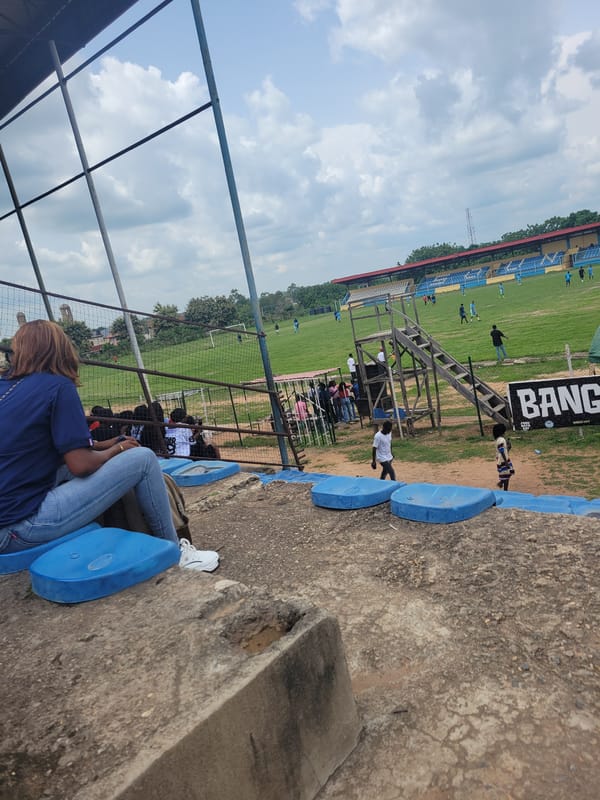 Soccer match draws spectators to outdoor stadium with blue seating
