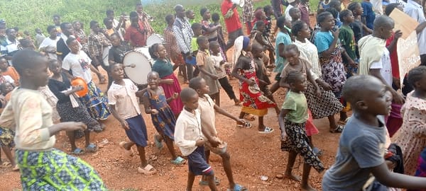 Children and adults march with banners in DRC communities