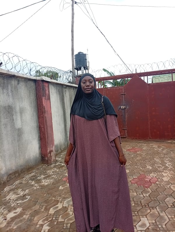 Woman stands by locked gate in Rido, Nigeria