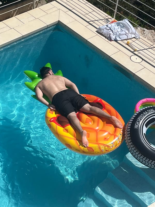 Man enjoys afternoon pool time on pineapple float in Spain