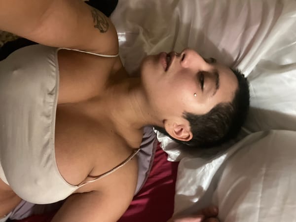 Person with tattoo rests on satin bedding in Buenos Aires