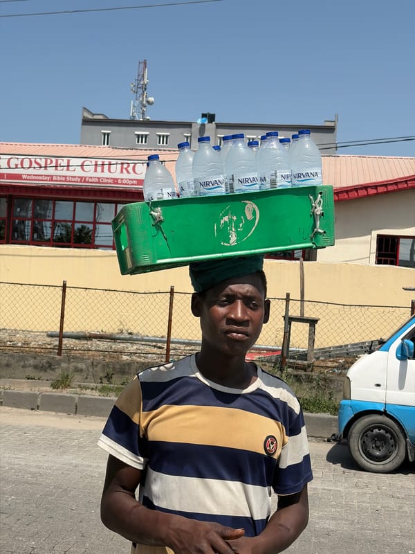 Street vendor carries water bottles in sunny Igboefon, Nigeria