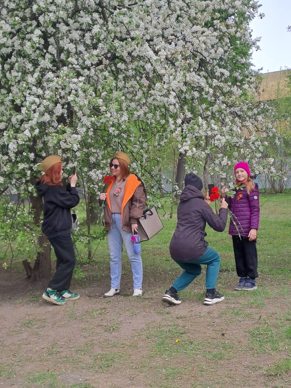 Four people gather near blooming tree in Elektrostal park